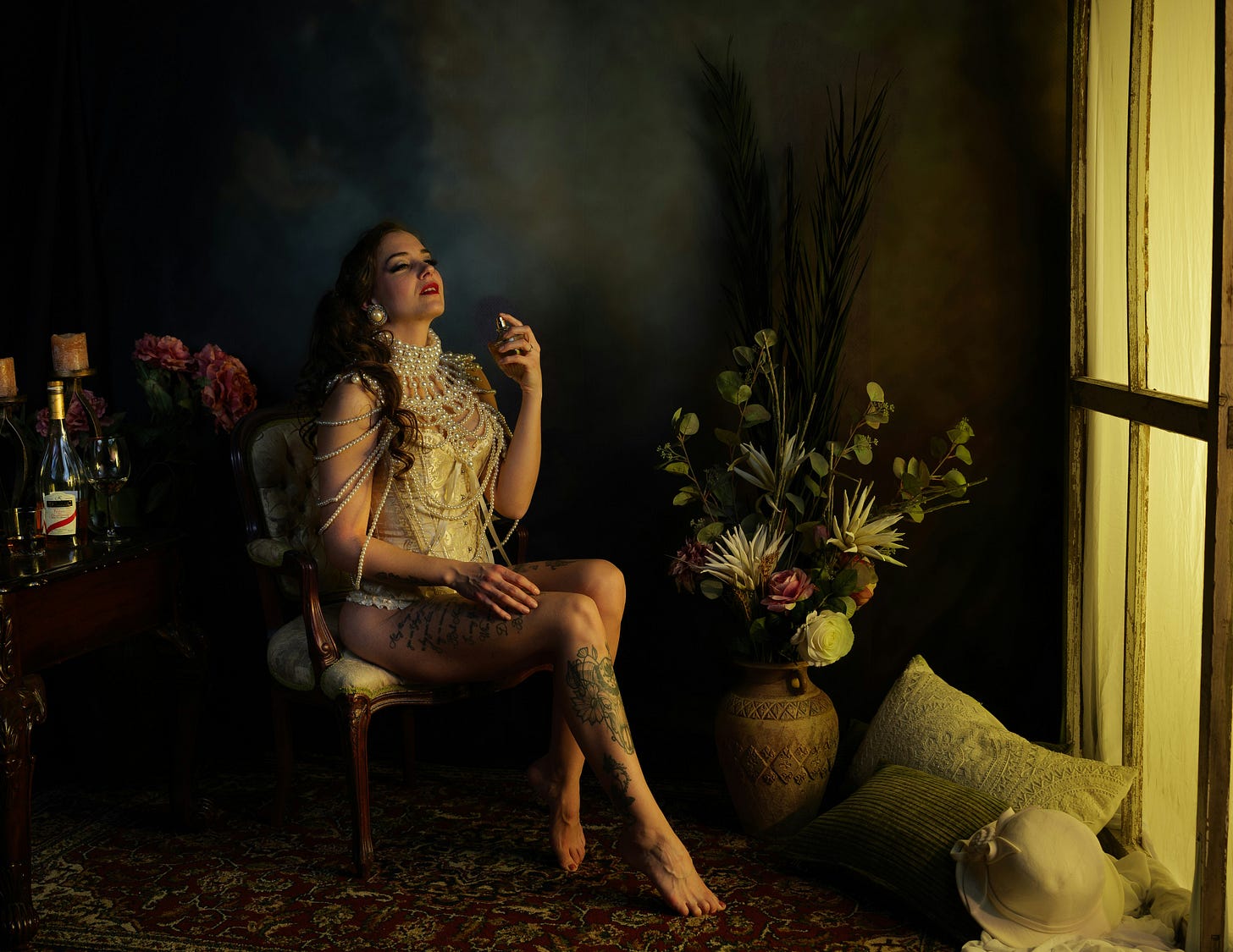 A woman sat down spraying perfume dressed in pearls