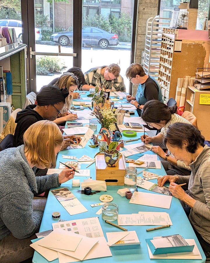Advertisement image for Inked Monoprint Postcards and Souvenir Sketchbooks workshop. Image of students in workshop.