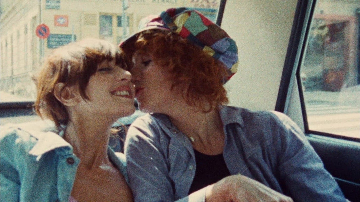In the back of a taxi, Dominique Labourier as Julie, a young white redhead, gleefully kisses the cheek of a grinning Celine, a young white brunette played by Juliet Berto In the back of a taxi, Dominique Labourier as Julie, a young white redhead, gleefully kisses the cheek of a grinning Celine, a young white brunette played by Juliet Berto