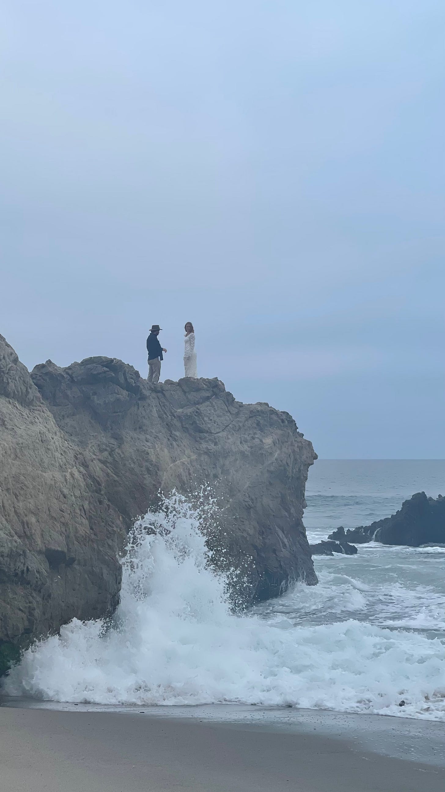 Danielle LaRauf in a wedding dress stands on the edge of a cliff overlooking turbulent ocean waves in The Not