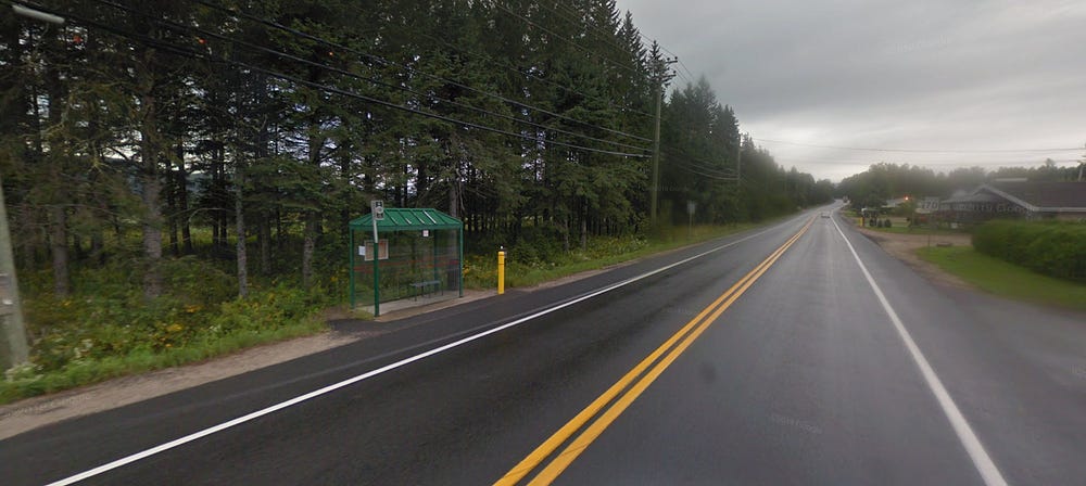 A highway with wide shoulders and a transit stop including a shelter.