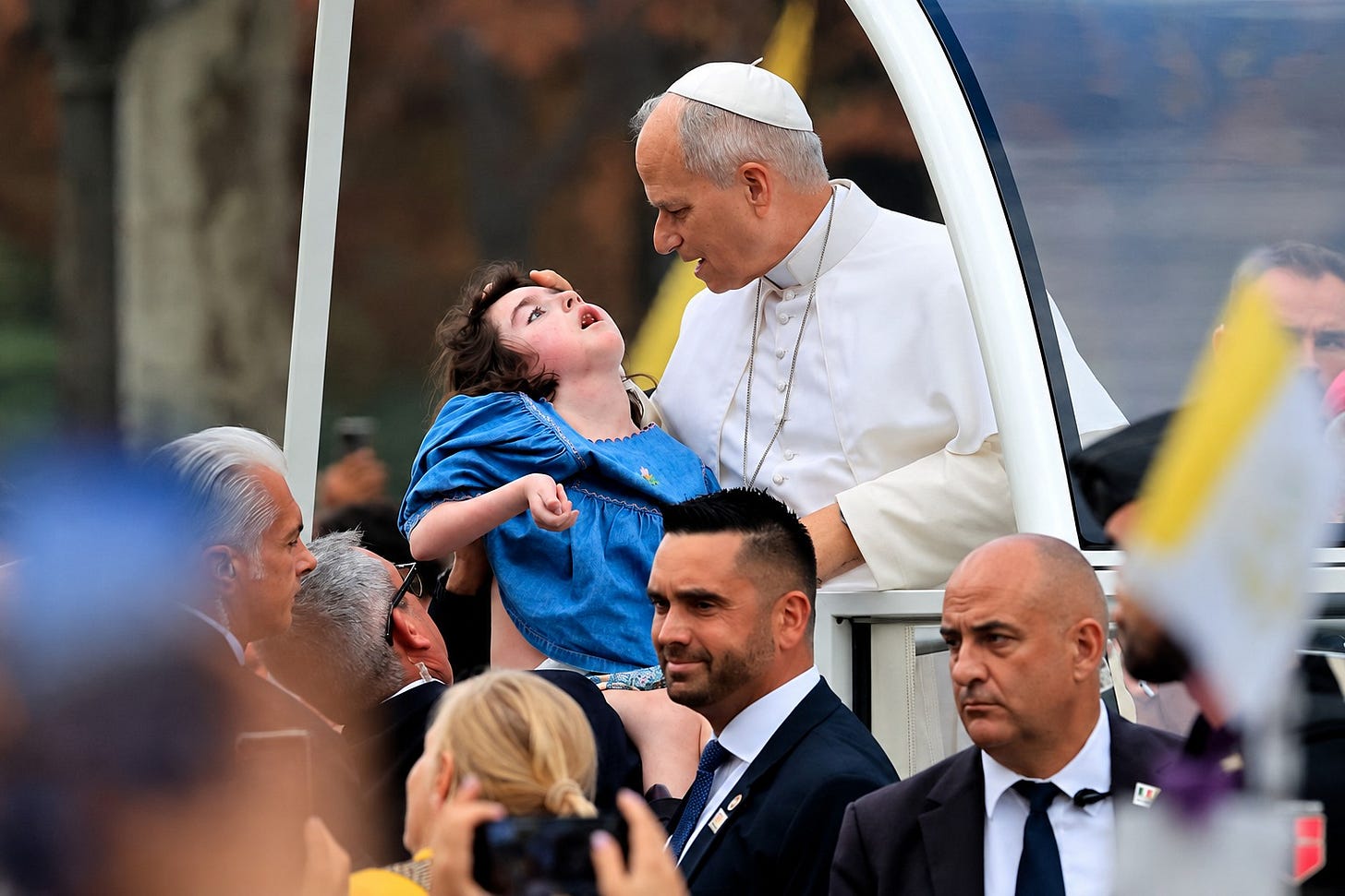 Pope Leo XIV blesses a girl with disabilities lifted up to the popemobile on the Champs-Élysées Pope Leo XIV blesses a girl with disabilities lifted up to the popemobile on the Champs-Élysées