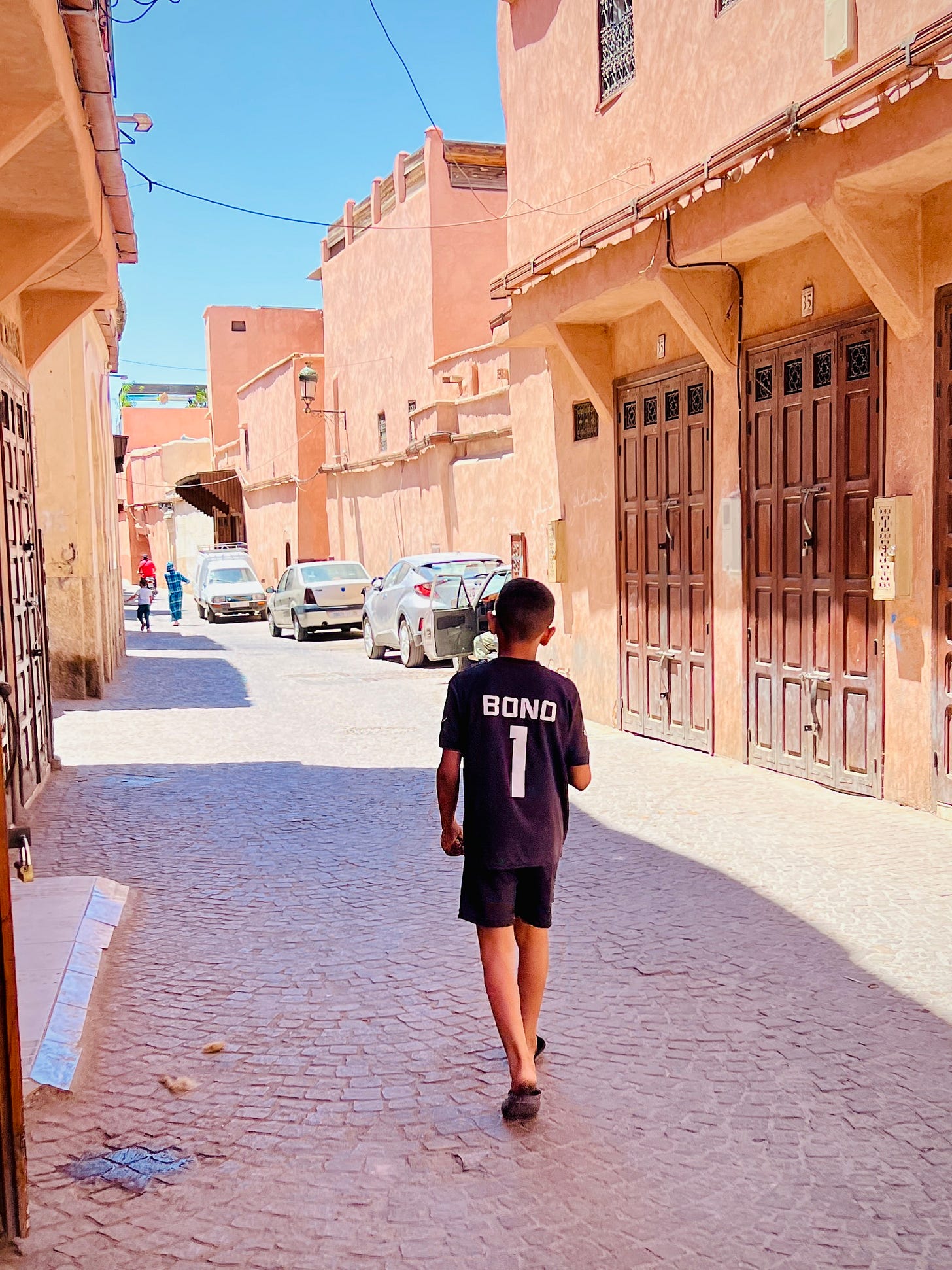 A young boy walks through a quiet street in Marrakech wearing a Morocco jersey with "Bono 1" on the back—a sight that was almost impossible before the 2022 World Cup.