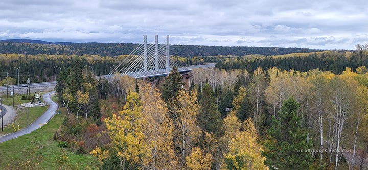 Image 1: A view of the modern, cable-stayed bridge spanning a wide river. Image 2: A view looking away from the bridge, where the dark river water flows out toward the open expanse of Lake Superior.