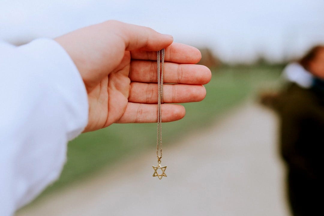 person holding gold cross pendant necklace