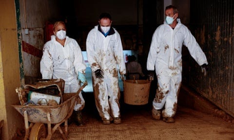 Volunteers carry mud out of a garage nearly a month after severe flooding in Paiporta, Valencia, Spain, 28 November 2024.  