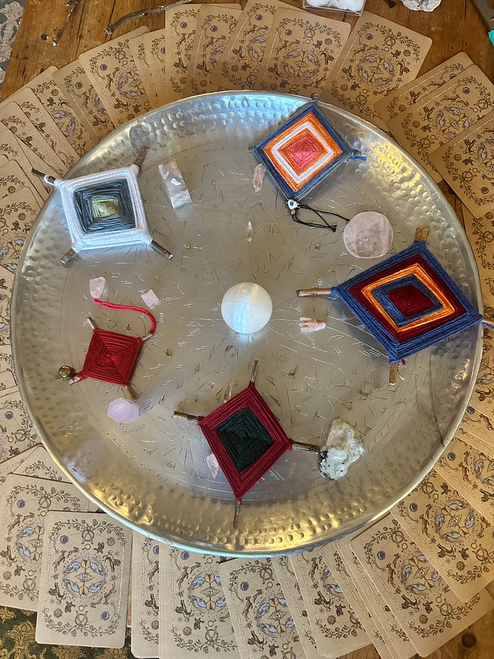 A fireplace decorated with flags and a plant showing candles and fairy light. A silver dishing holding a crystal grid surrounded by oracle cards.