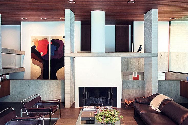 This may contain: a living room filled with furniture and a fire place in front of a painting on the wall