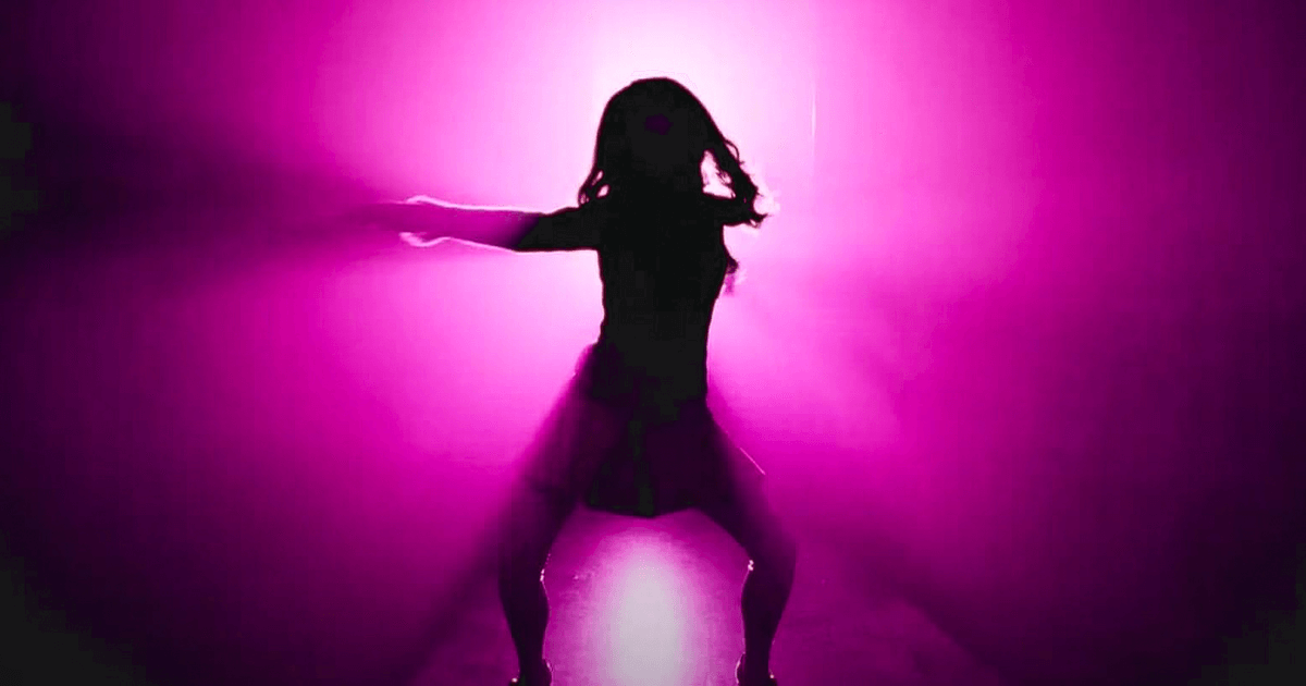 M3GAN dancing, arm outstretched, in sillouette against a pink lit background. M3GAN dancing, arm outstretched, in sillouette against a pink lit background.
