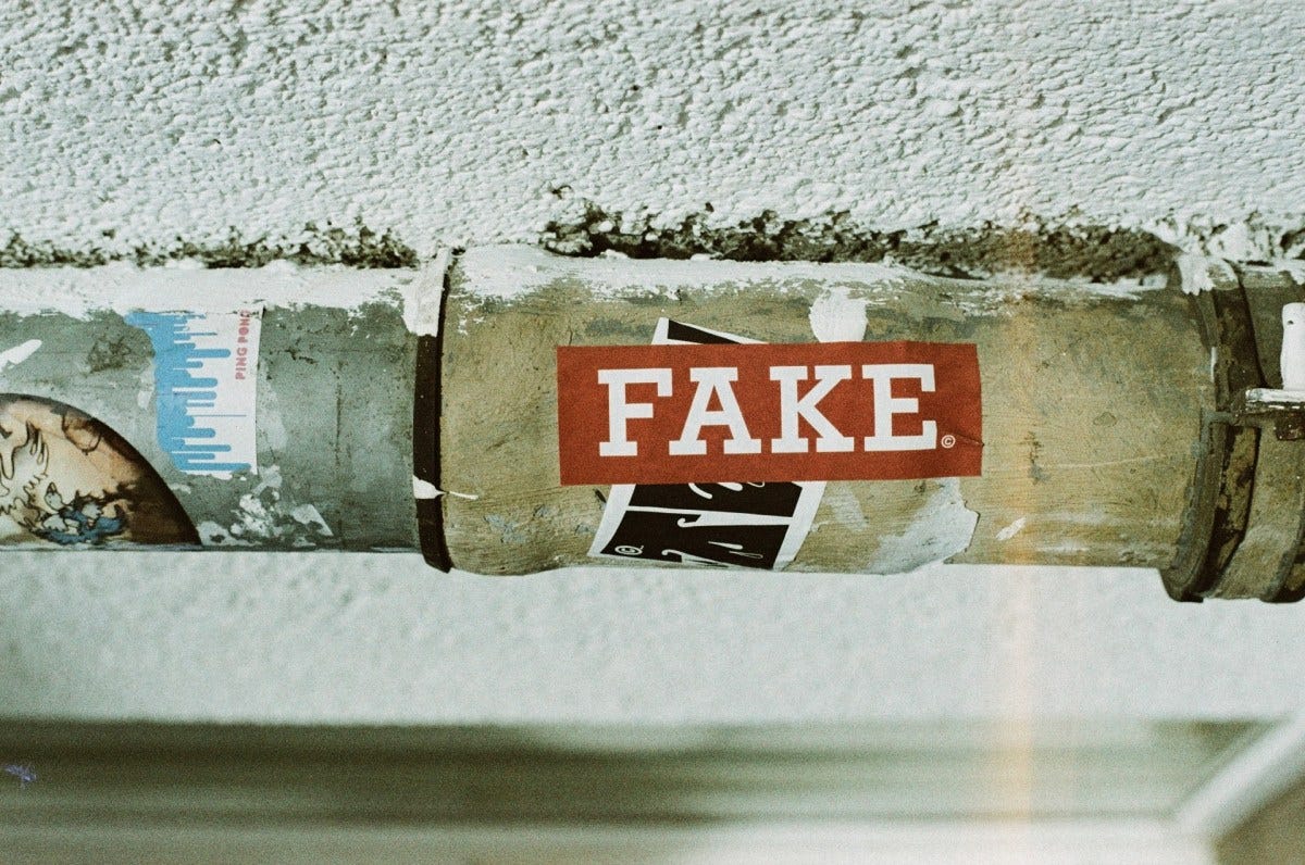 A sticker on a lamp post reading 'Fake'