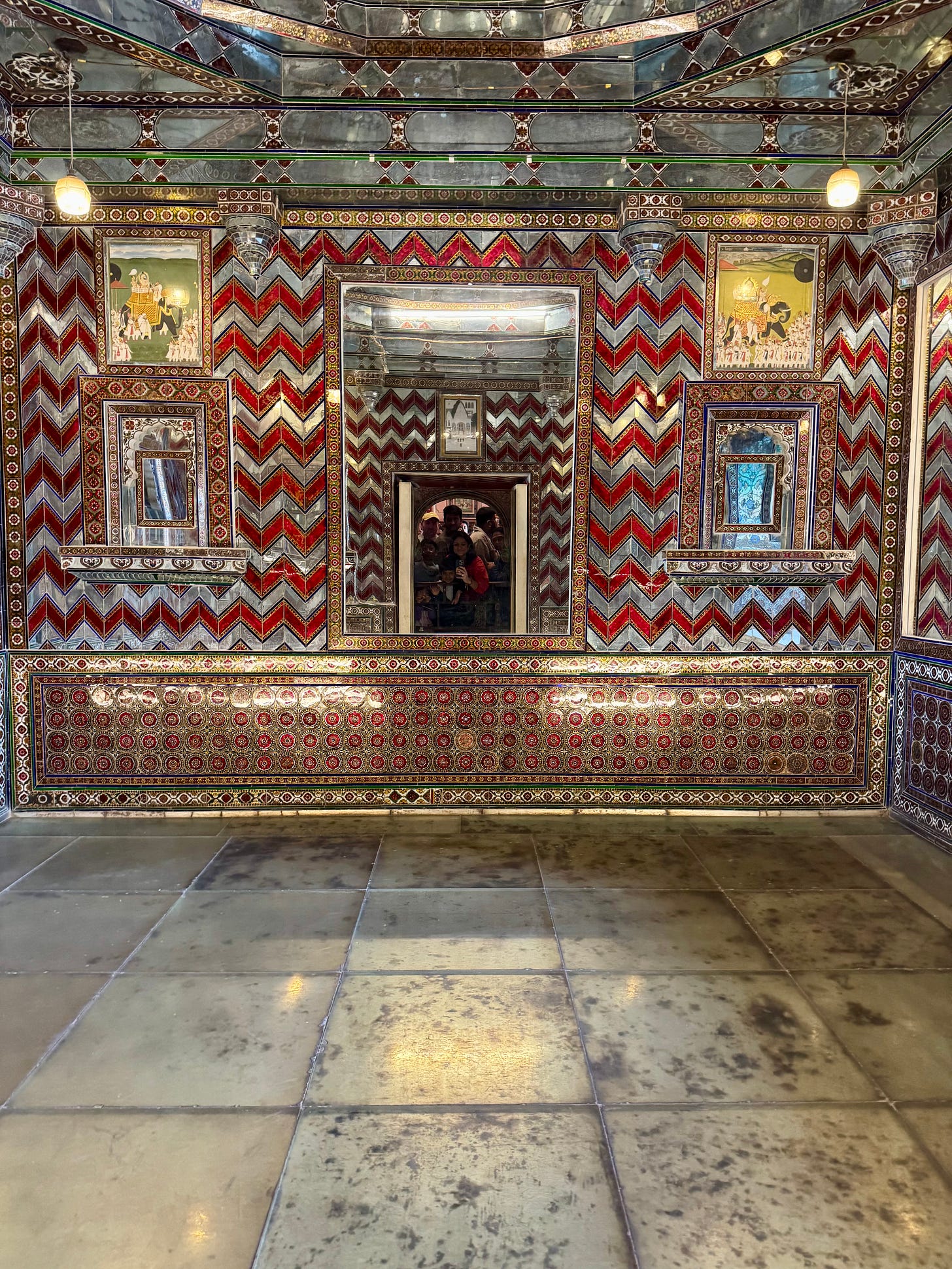Interior room covered in mirrored mosaic and geometric patterns with reflective surfaces.