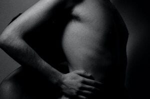a naked man holding his stomach in ain.
