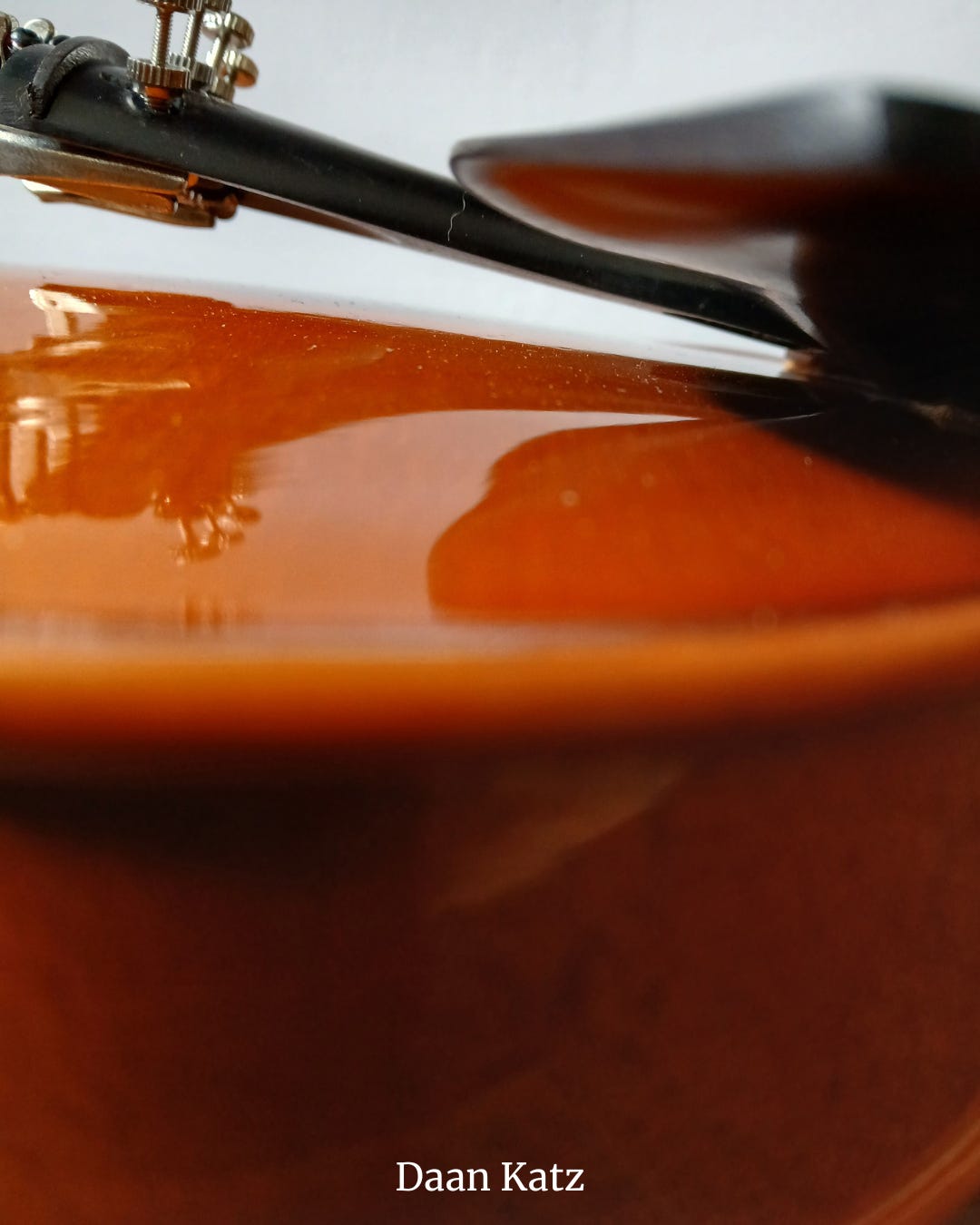 Close-up of the violin's curved lower bout with chin rest, tail piece, and fine tuners..