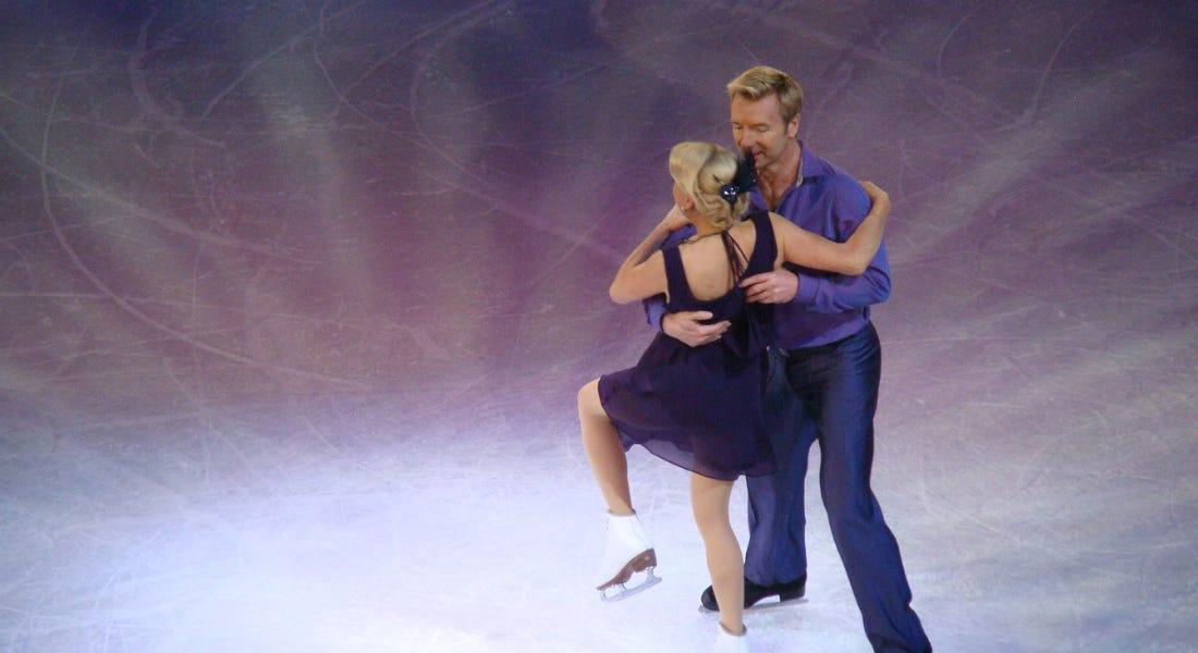 Two ice skaters - Torvill and Dean - skating on an ice rink with purple lighting Two ice skaters - Torvill and Dean - skating on an ice rink with purple lighting