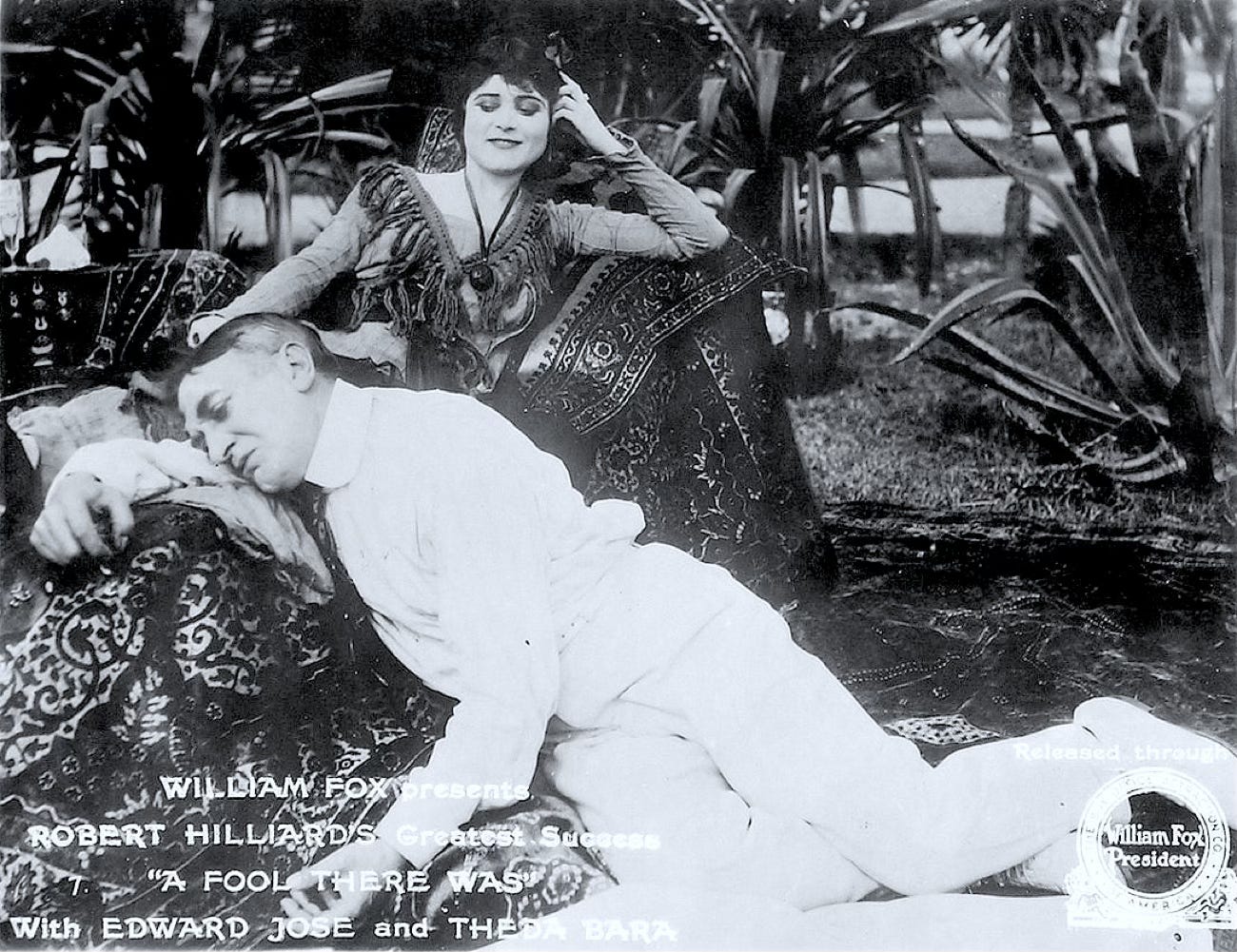 Promotional photo for the 1915 film “A Fool There Was” features Theda Bara and costar Edward Jose. She reclines on a chaise longue and gazes down contemptuously at Jose, who is collapsed on the ground beside her with his head resting on her lap.