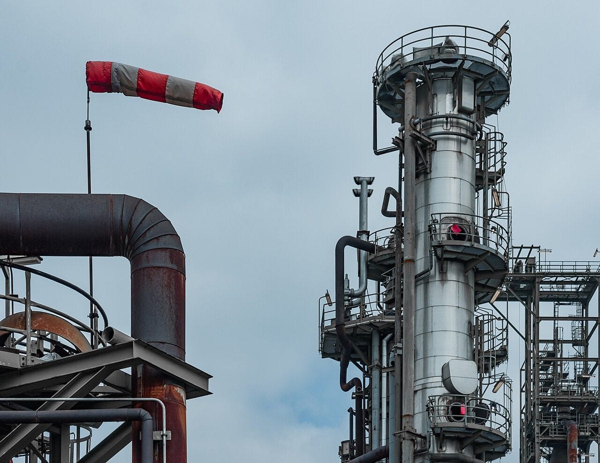 Distillation column and pipes at a petrochemical plant under a windsock