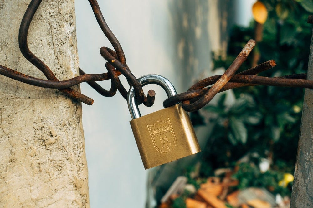 brass padlock on brown metal fence brass padlock on brown metal fence