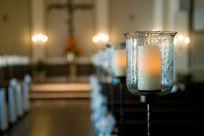 This is a photo of a church aisle with a candle in the forefront. This is a photo of a church aisle with a candle in the forefront.