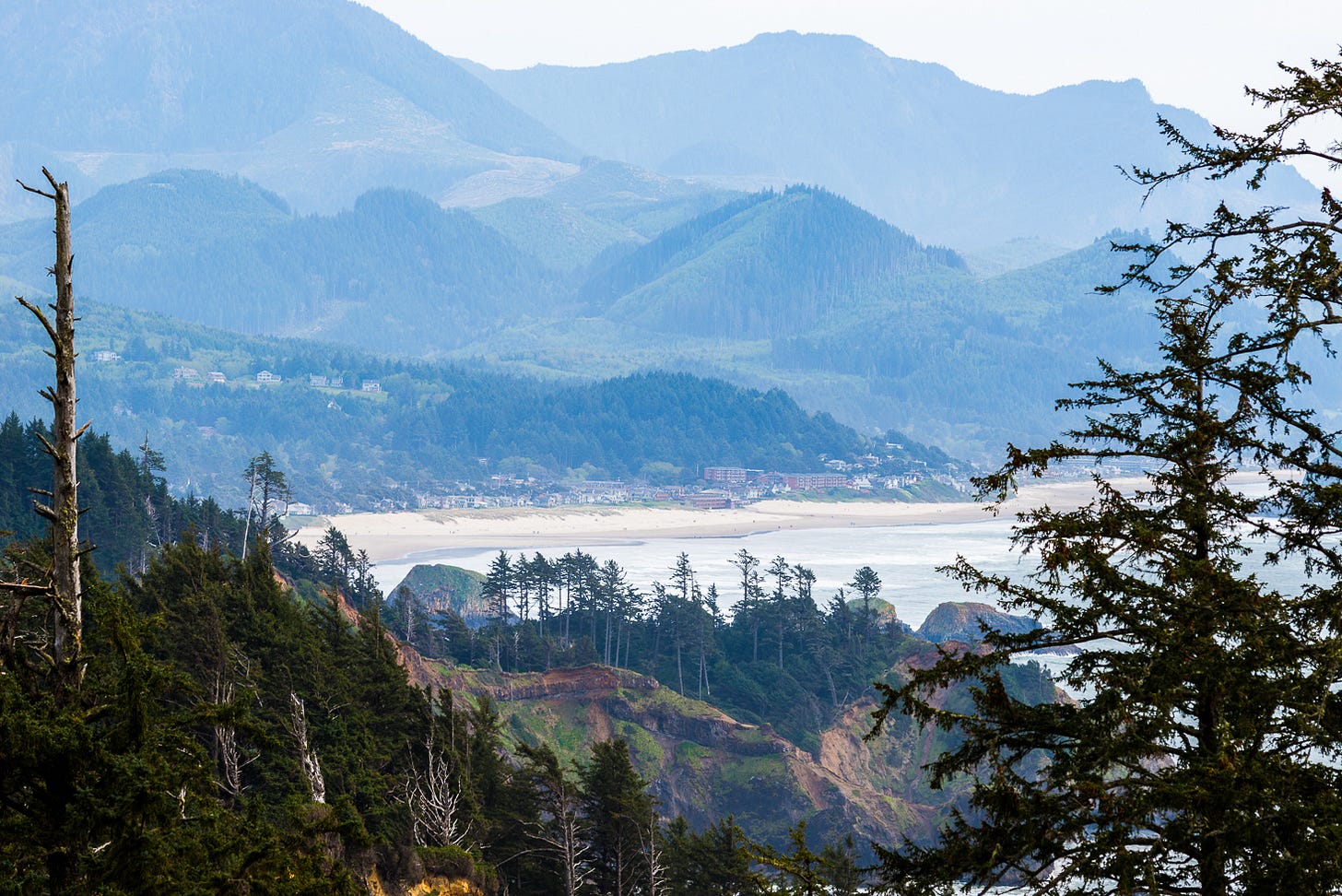 Seaside town below cascading mountains.