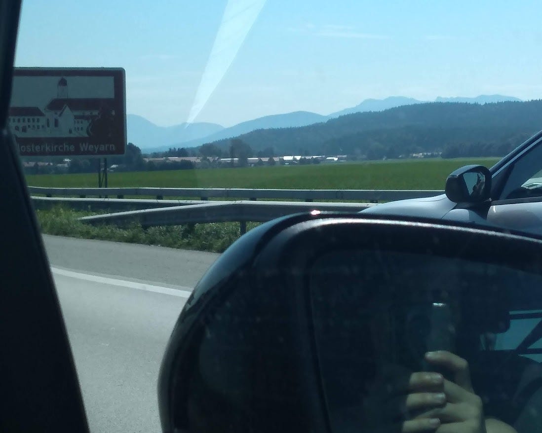 Shot of a car wing mirror from inside the car, with a background of mountains and valleys