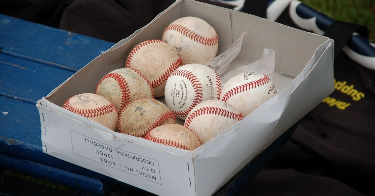 Photo: Pixabay / Pexels A box full of used baseballs sitting on a blue bench outdoors, perfect for sports enthusiasts.
