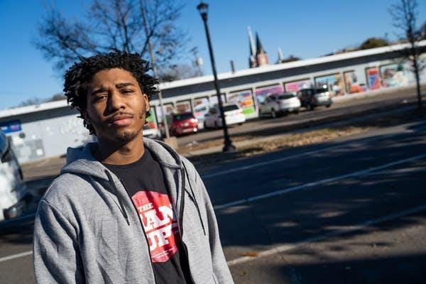 A man stands across the street from a mural.