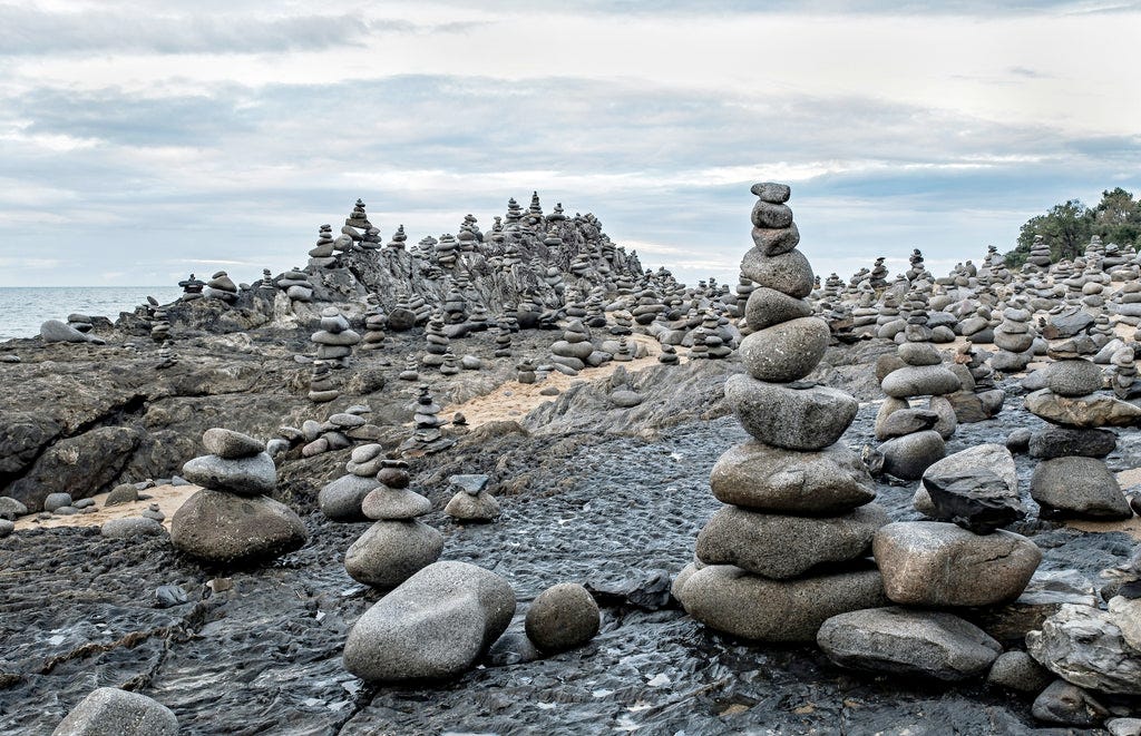many piles of small stones on a rocky coastline