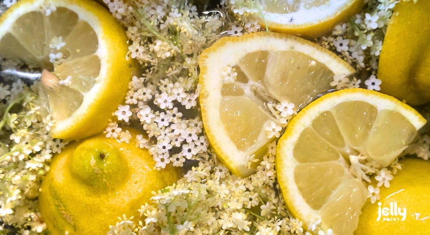 Близък кадър на цветове от бъз и лимони, потопени във вода.