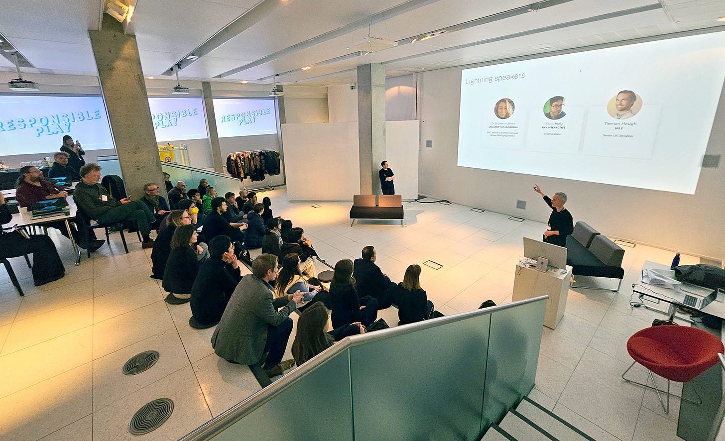 A large audience listens to speakers in a bright open venue. A huge screen shows biographies of speakers. Other screens in the background say 'Responsible Play'