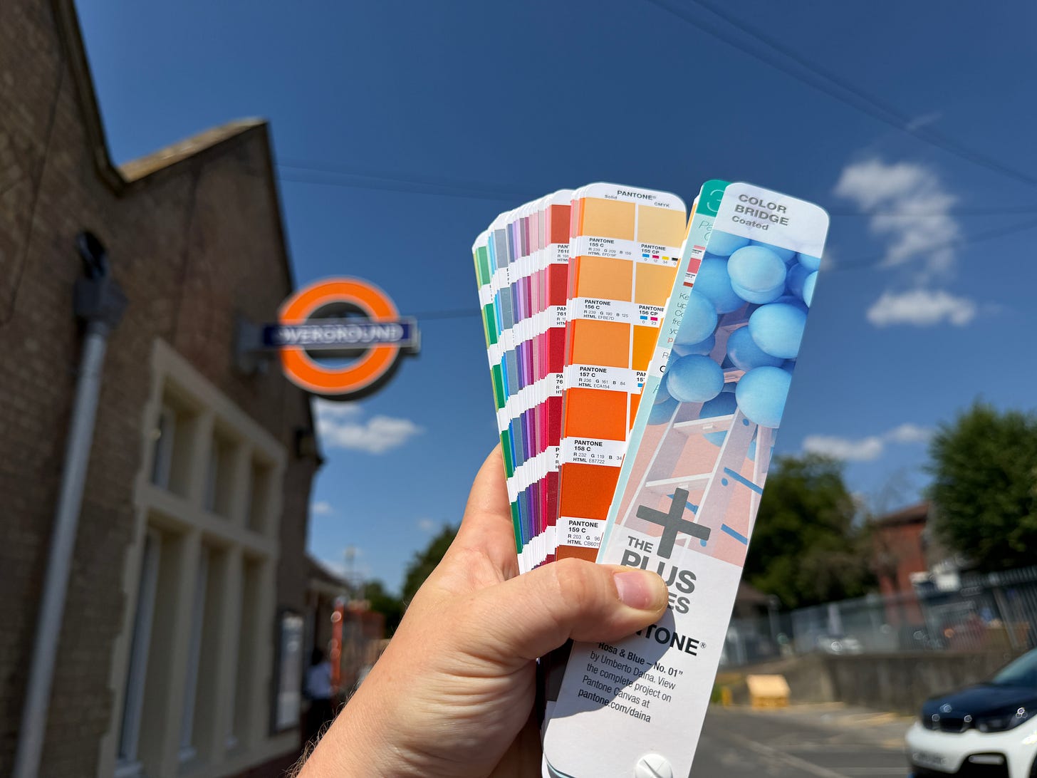 Photo showing Pantone colour book held up against Overground roundel.
