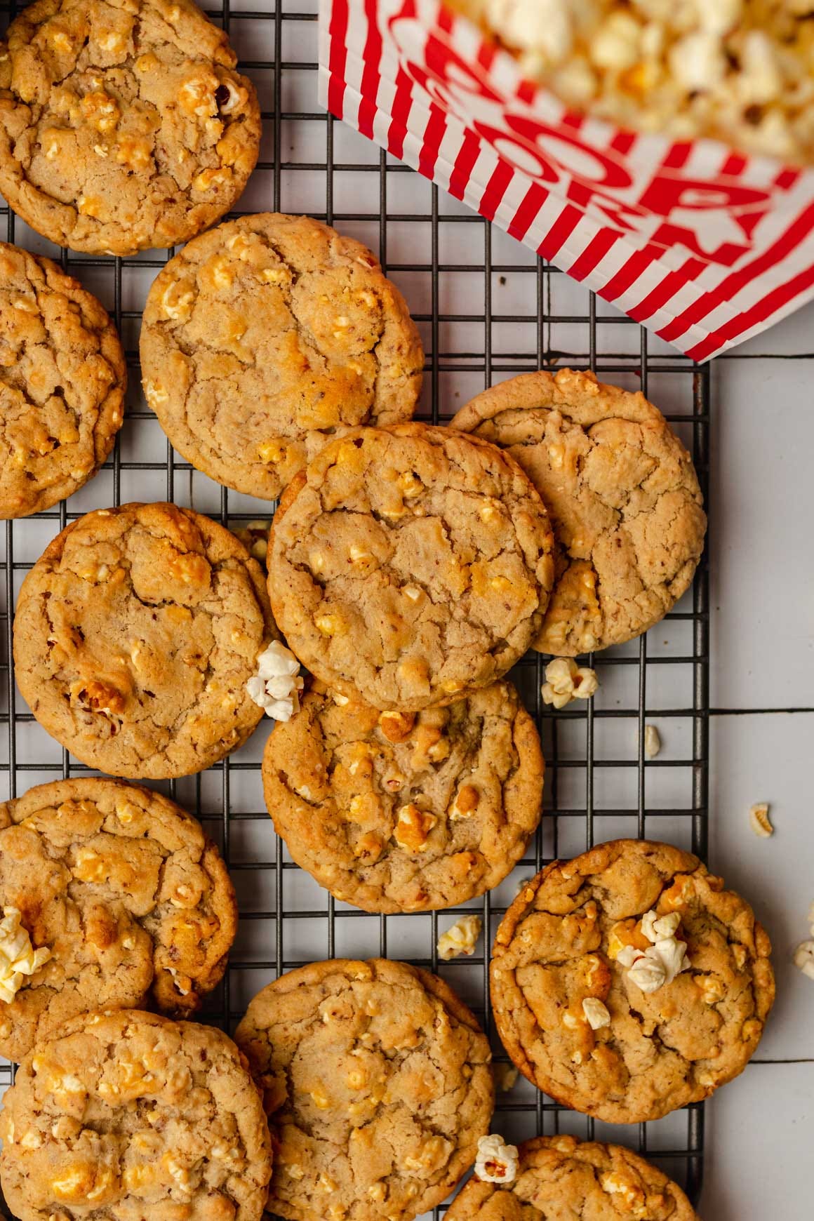 Top down shot of vegan popcorn cookies on a rectangle wire rack with a bag of popcorn in the top right corner. 