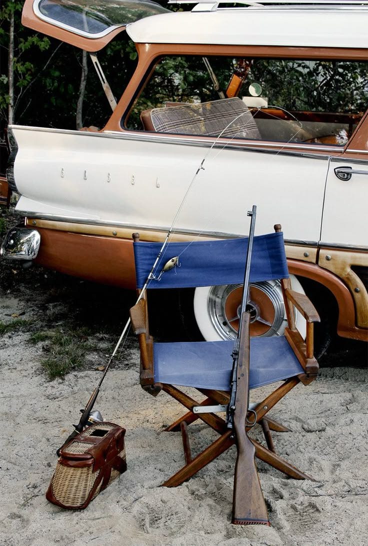 This may contain: an old boat sitting in the sand next to a blue chair with a fishing pole on it This may contain: an old boat sitting in the sand next to a blue chair with a fishing pole on it