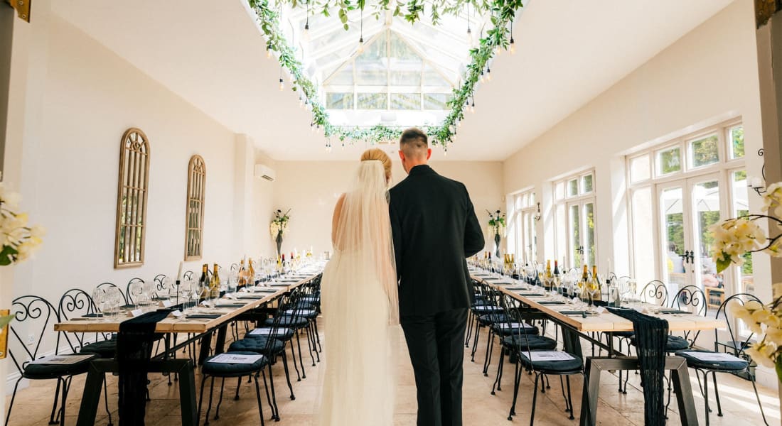 A bride and groom looking onto a dining hall with a sky ceiling above them A bride and groom looking onto a dining hall with a sky ceiling above them