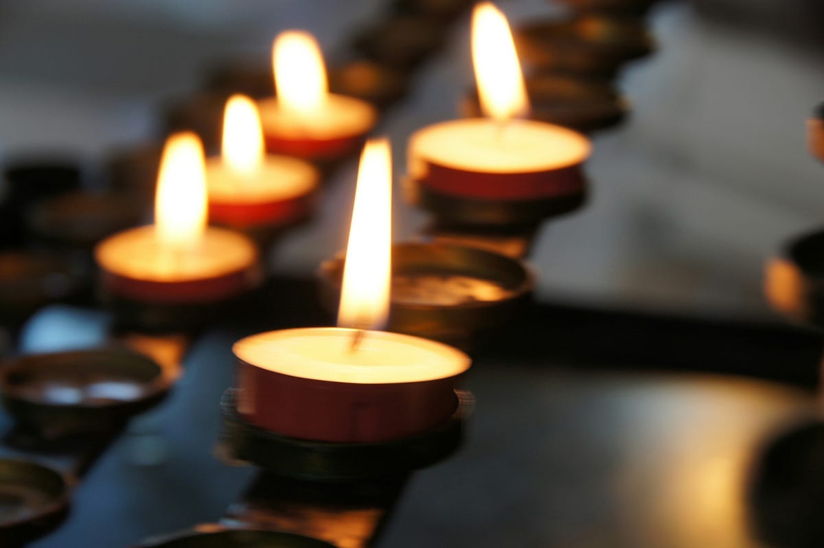 5 lit votive candles close-up on a brass stand of holders Photo by Eli Solitas on Unsplash