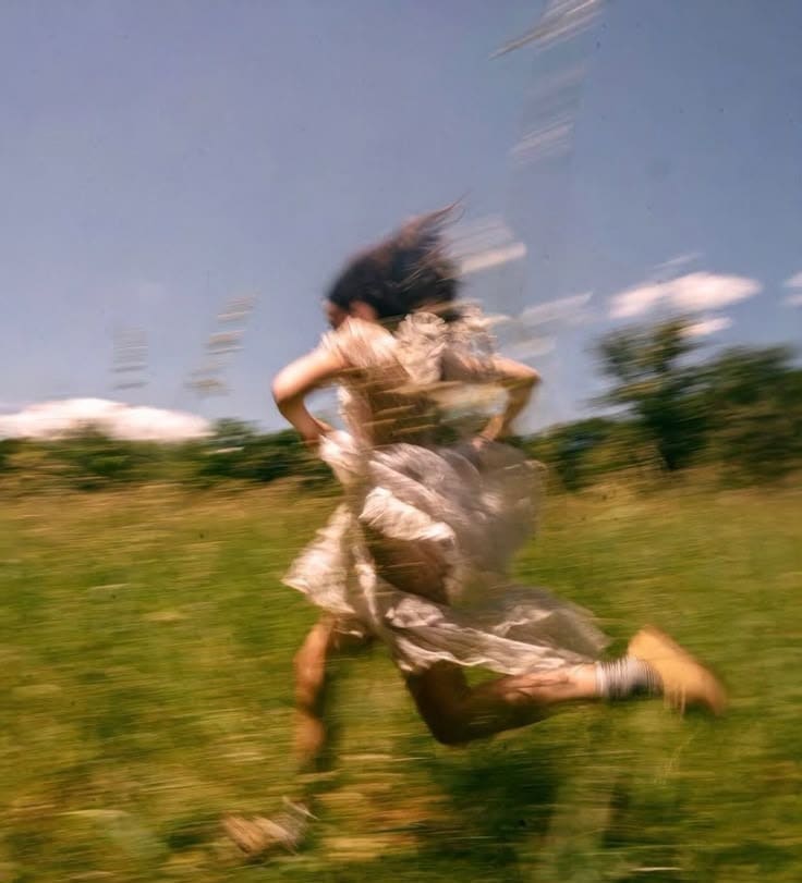 This may contain: a blurry photo of a woman running in the grass This may contain: a blurry photo of a woman running in the grass