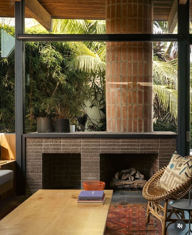 This may contain: a living room filled with furniture and a fire place in front of a brick fireplace