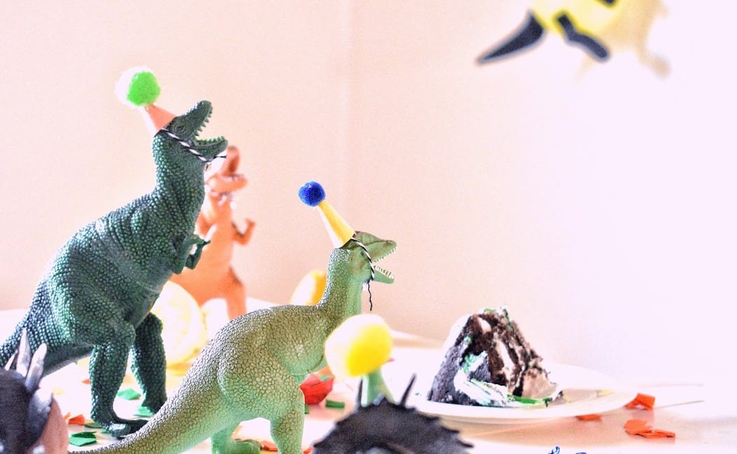 assorted-color dinosaur toys near slice cake on white table assorted-color dinosaur toys near slice cake on white table