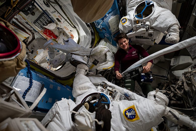 a woman is surrounded by multiple spacesuits