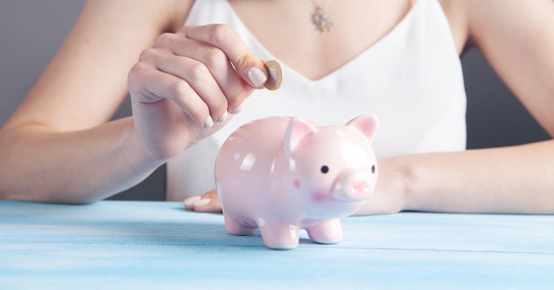 woman in white tank top holding pink pig figurine