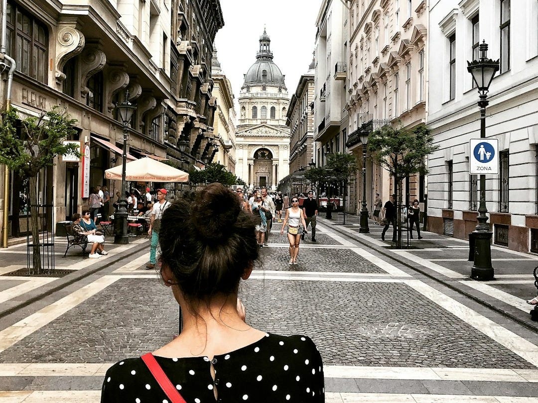 woman in black and white polka dot shirt walking on sidewalk during daytime woman in black and white polka dot shirt walking on sidewalk during daytime