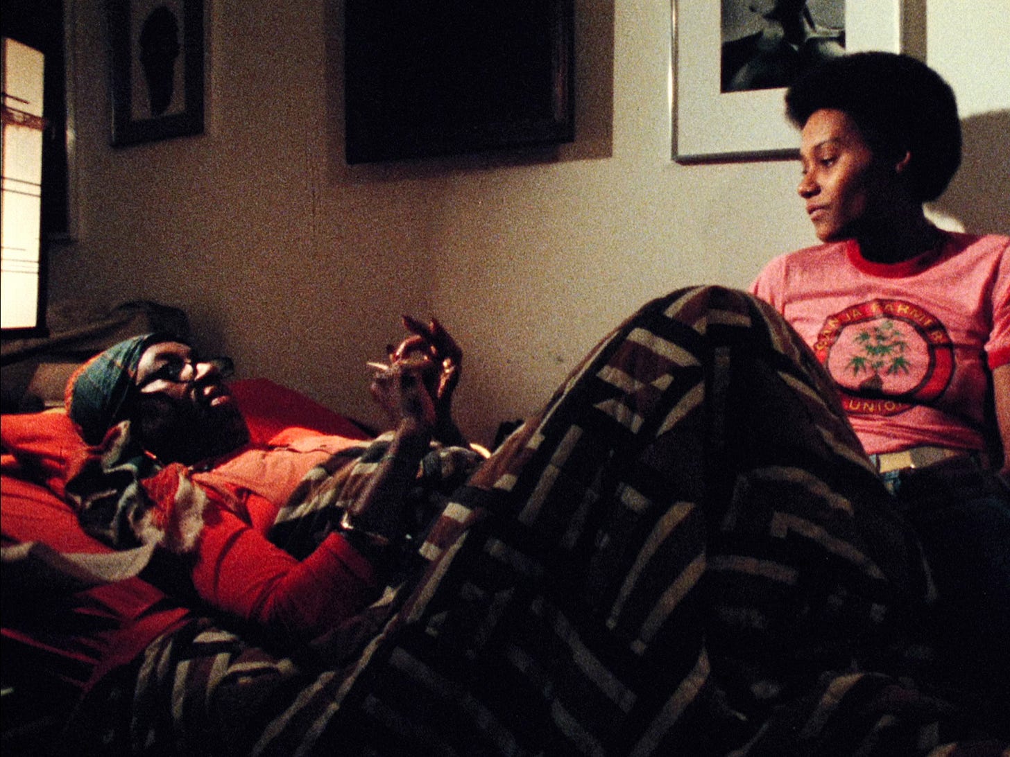 Two women lounging in a low-lit bedroom