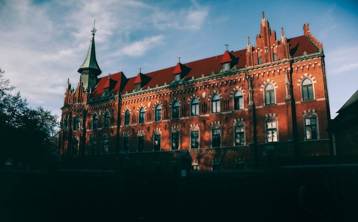 Free Stunning Gothic-style seminary building in Krakow, Poland, captured at sunset with dramatic shadows. Stock Photo
