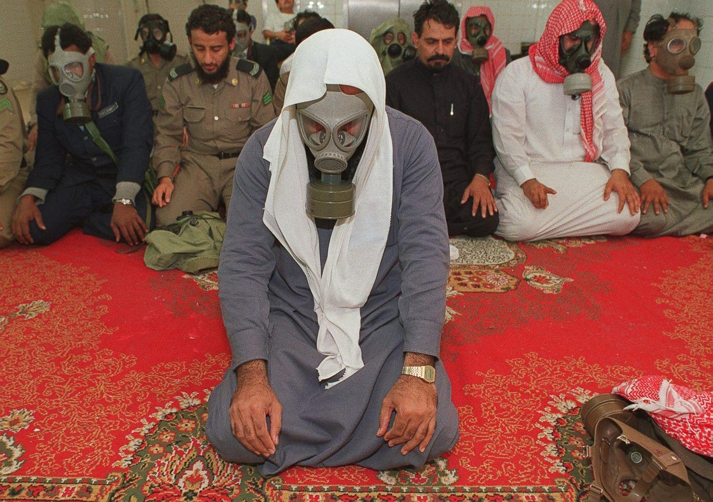 r/HistoryPorn - Soldiers, hotel workers and others, some wearing gas masks, kneel for morning prayers on Jan. 18, 1991 in a basement used as a bomb shelter at a hotel in eastern Saudi Arabia during the Gulf War [1600 x 1127]