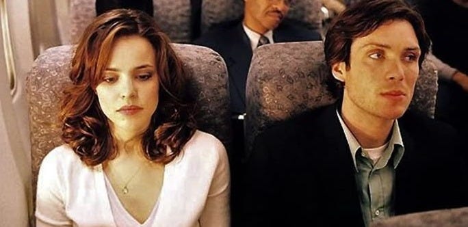 This may contain: two people are sitting on an airplane and one person is looking at something in the distance
