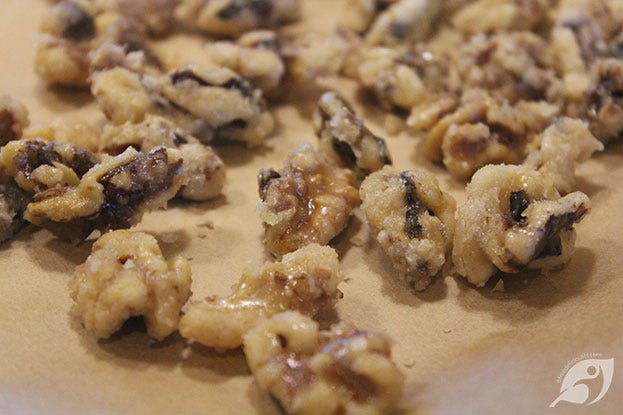 Pecans and walnuts spread out on parchment paper to cool and dry.