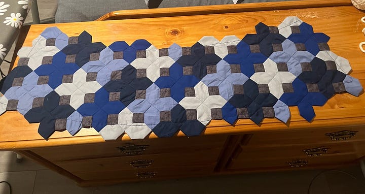 Photos of fabric lampshade pieces laid out flat. One is a solid light blue with interfacing attached to the wrong side. The other is a patchwork of blue crosses and grey squares