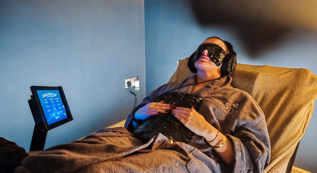 A woman - Eve Smallman - wearing a dressing gown, eye mask, and chest plate on a lounger A woman - Eve Smallman - wearing a dressing gown, eye mask, and chest plate on a lounger