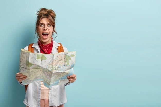 Photo of frustrated woman traveler lost in city, looks depressed at paper map, shouts from despair Free Photo
