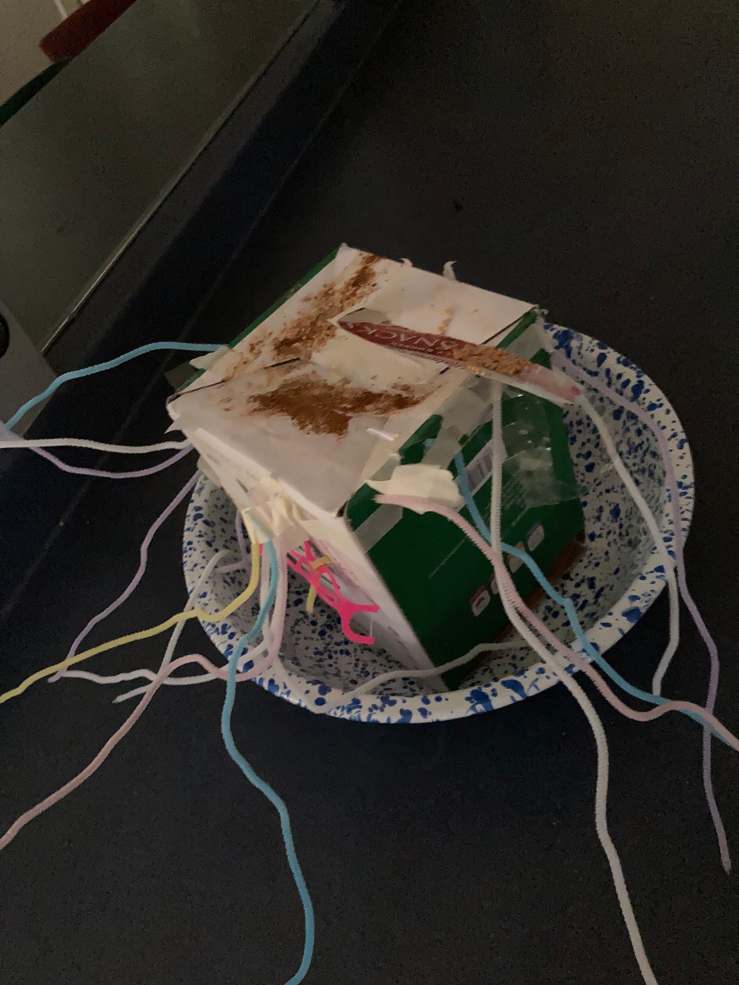 a box with pipe cleaners coming out, sitting in an enamel basin a box with pipe cleaners coming out, sitting in an enamel basin