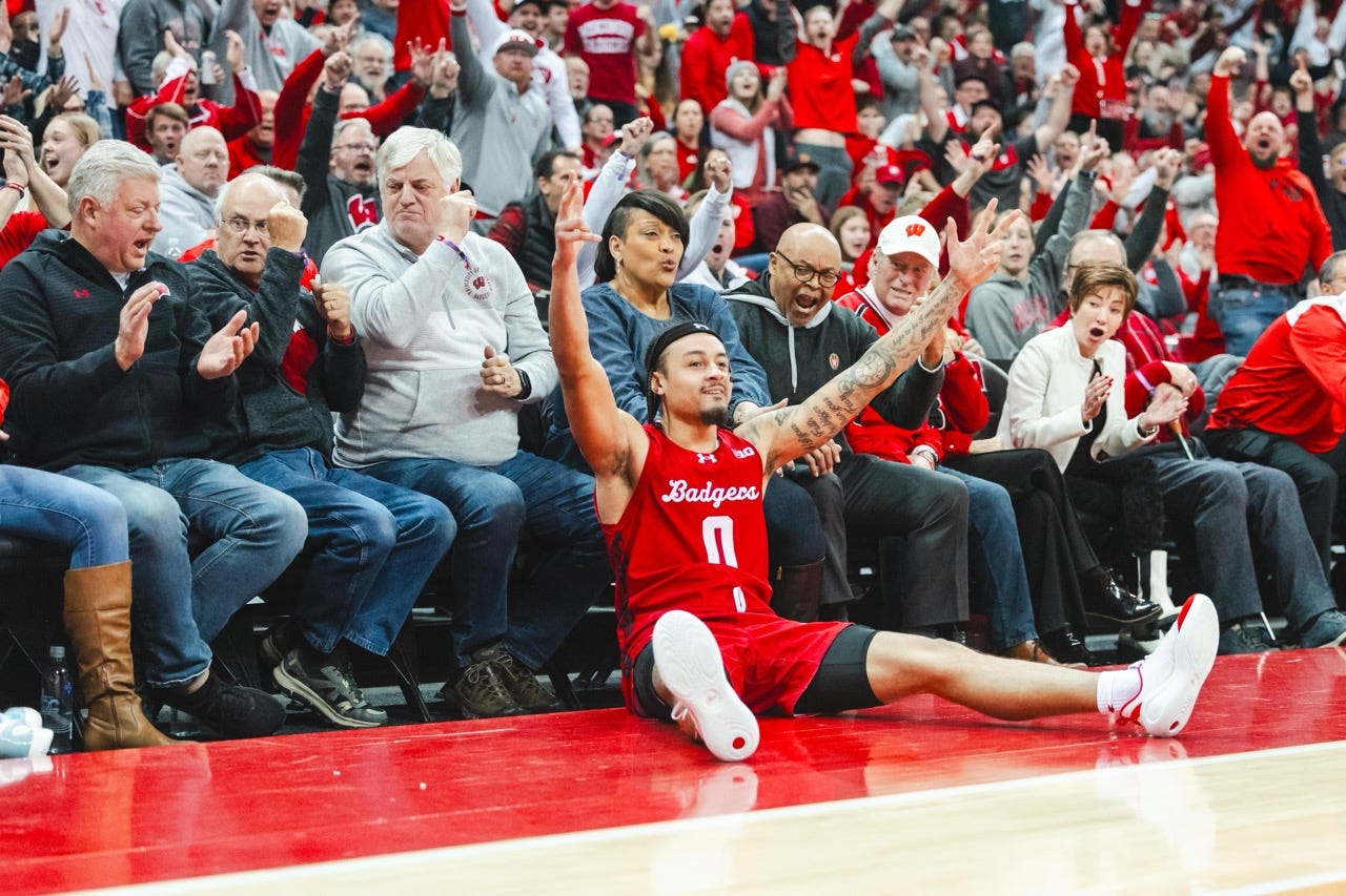 carrington throws his arms up in the air while seated on the baseline with fans behind him cheering carrington throws his arms up in the air while seated on the baseline with fans behind him cheering